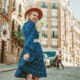 A woman in a plaid skirt and red beret walks down the streets of Paris, looking over her shoulder, knowing what to wear to Paris in September.