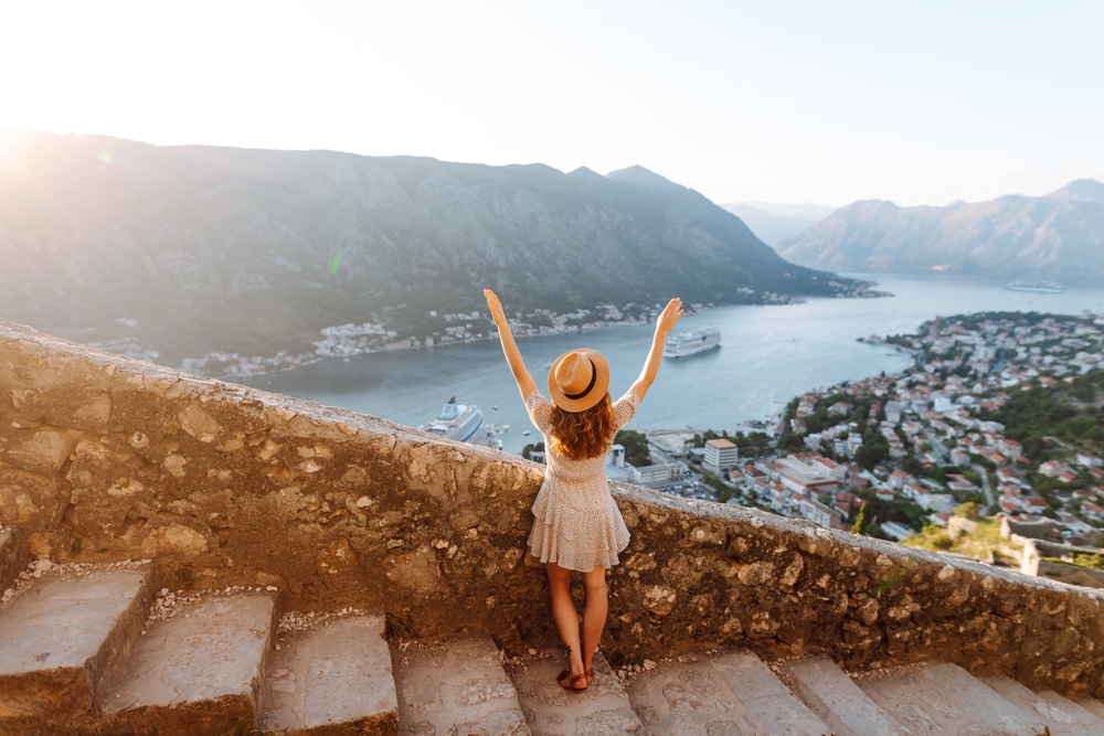 Back view of Tourist woman standing on the observation deck admiring view of colorful the view of the city. Europe travel. Article is about a 10 days in Europe packing list.