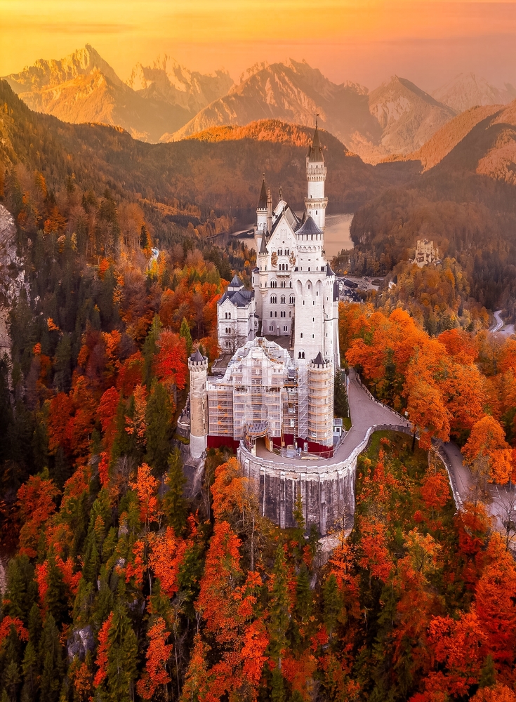 Under the golden twilight of the Bavarian mountains, Neuschwanstein Castle stands majestically amidst the blazing autumn colors. The article is about fairytale destinations.