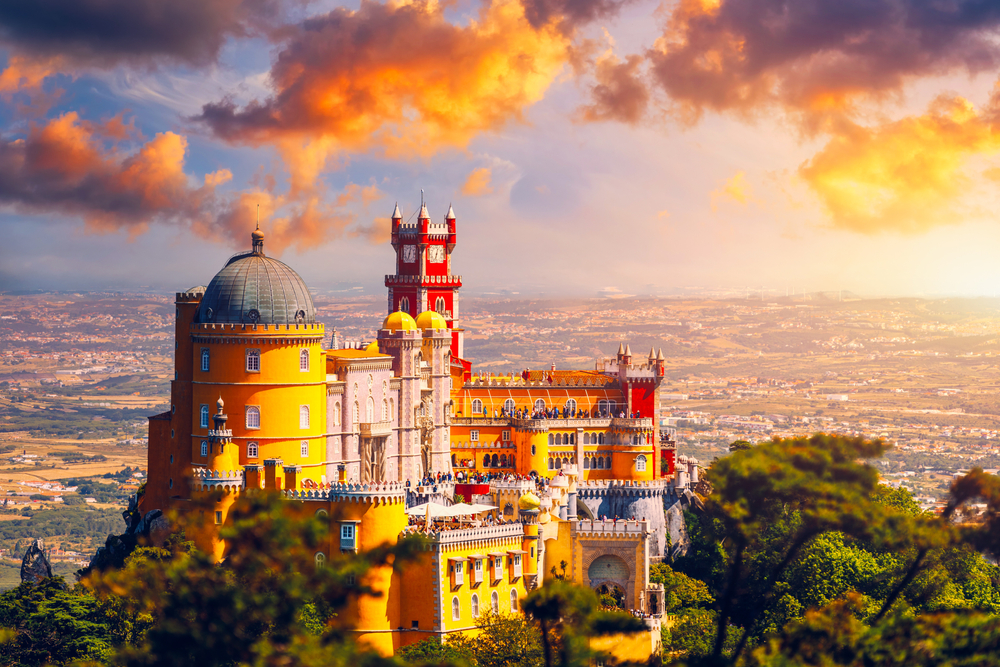 Famous historic Pena palace part of cultural site of Sintra against sunset sky in Portugal. The article is about fairytale destinations.