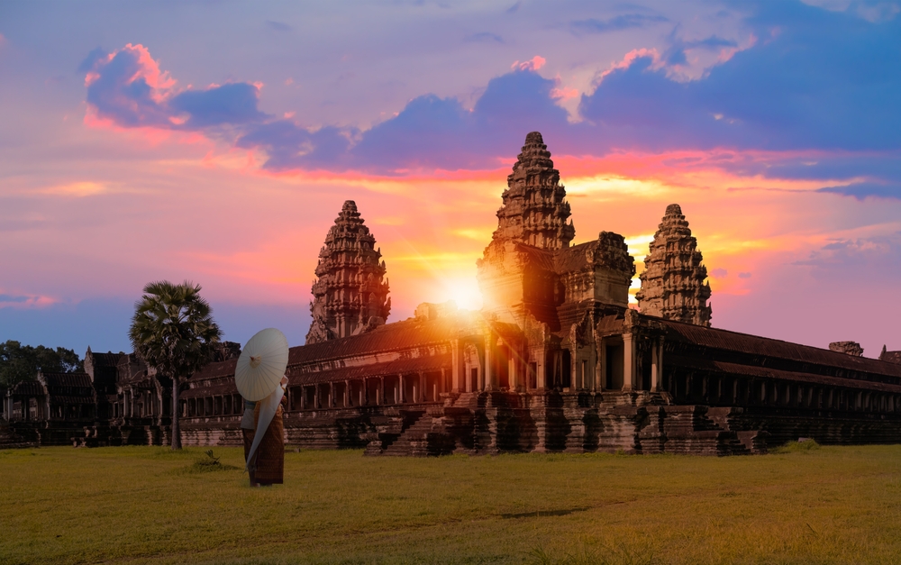 Angkor Wat temple Cambodia at sunrise. There is a person standing in front of the temple.