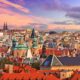 photo of sprawling prague cityscape at sunset, spires are reaching up over smaller buildings