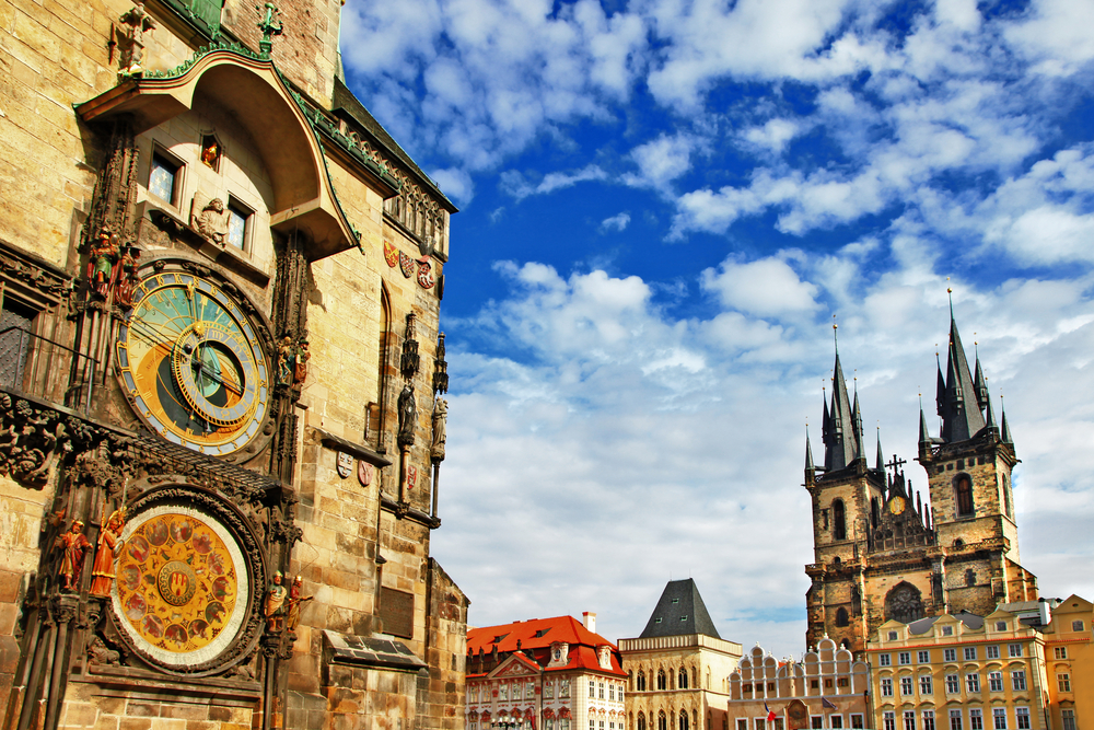 a bright day, the astronomical clock in prague is on the left and other buildings can be seen in the background.