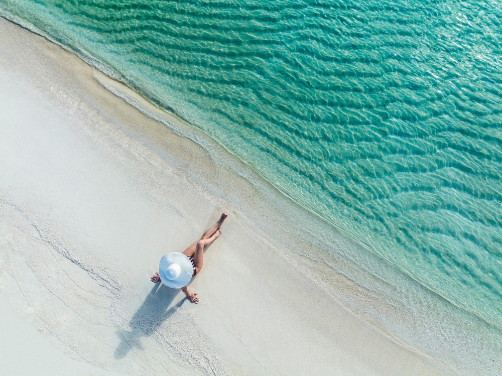 Woman on the background of the sea and sunny beach. The article is about things to buy from Amazon before your beach vacation.