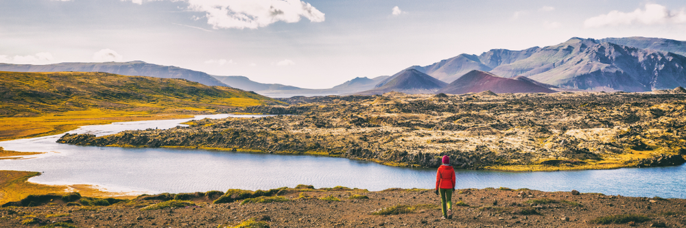 A tourist explores Icelands landscape in hiking pants, a red jacket, and a read beanie: as the greens fade into fall colors, the tourist knew what to wear to Iceland in the fall.