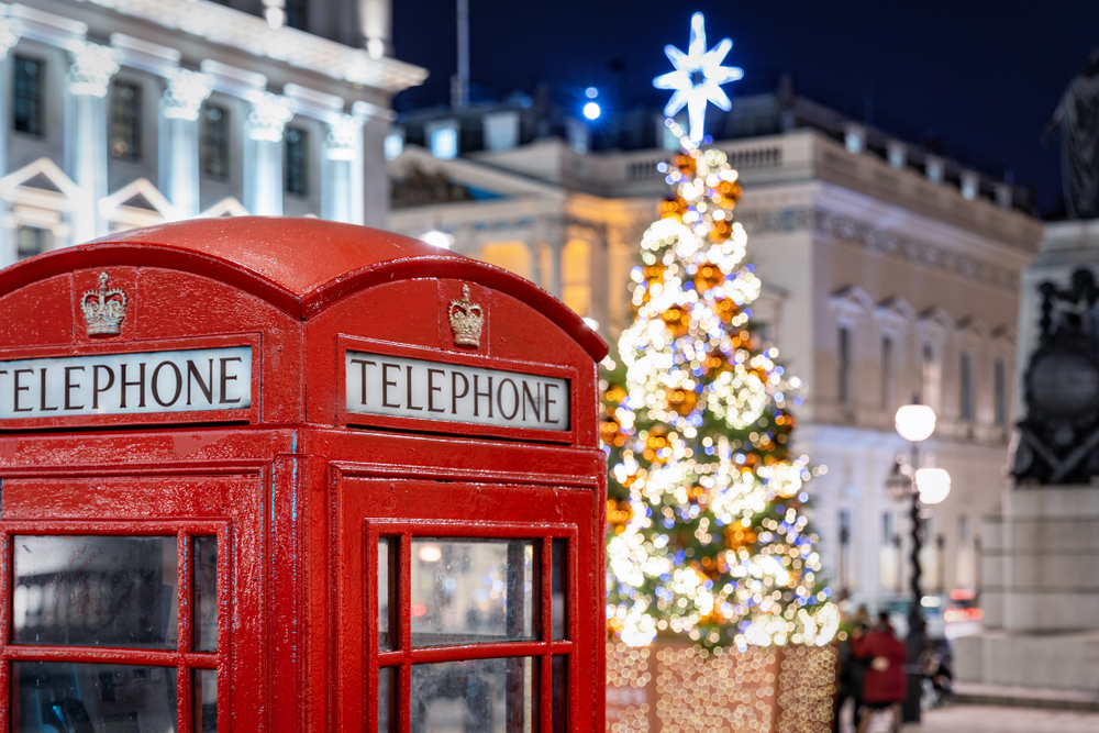 A shot of London shows a classic telephone booth being set aglow by a lit tree next to it, really setting the holiday spirit, which is one of the Christmas travel tips for a smoother winter vacation.