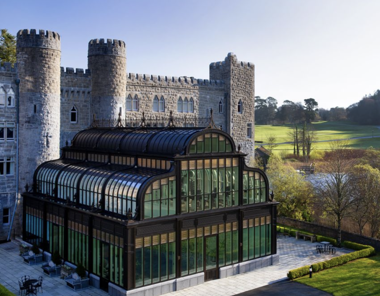 This photo of Ashford Castle in Ireland is one of the 10 Most Luxurious Hotels to Spend Christmas Around the World, as you can tell from the historic castle overlooking the water and greenhouse.
