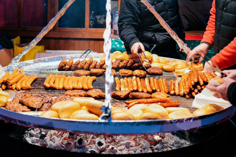 The food at the German christmas markets is sausages cooking on a large open grill