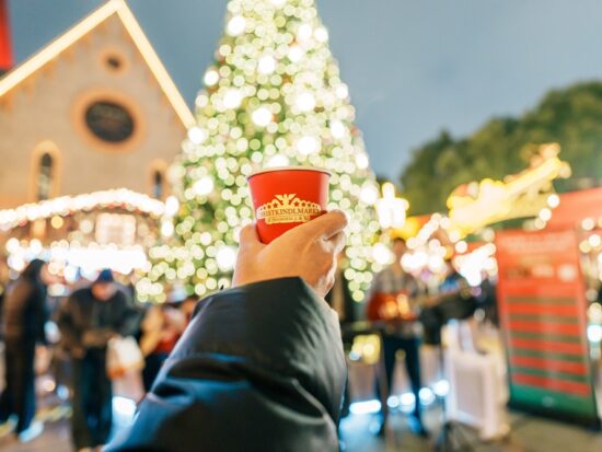 girl holding a cup in front of a christmas tree at one of the Christmas Markets in Europe
