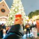 girl holding a cup in front of a christmas tree at one of the Christmas Markets in Europe