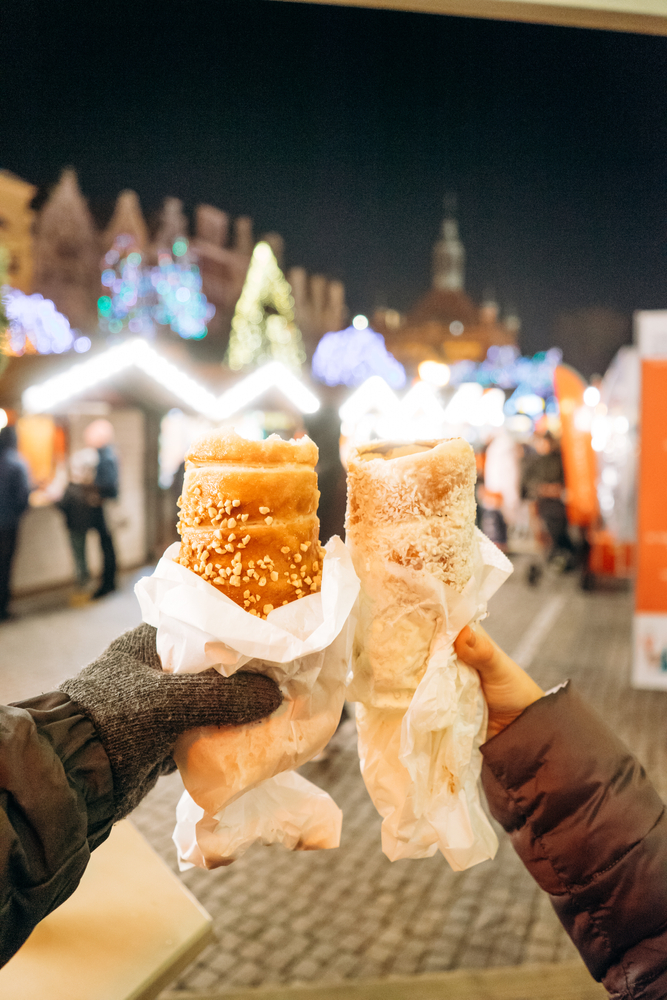 a couple with hands holding up food at the christmas market