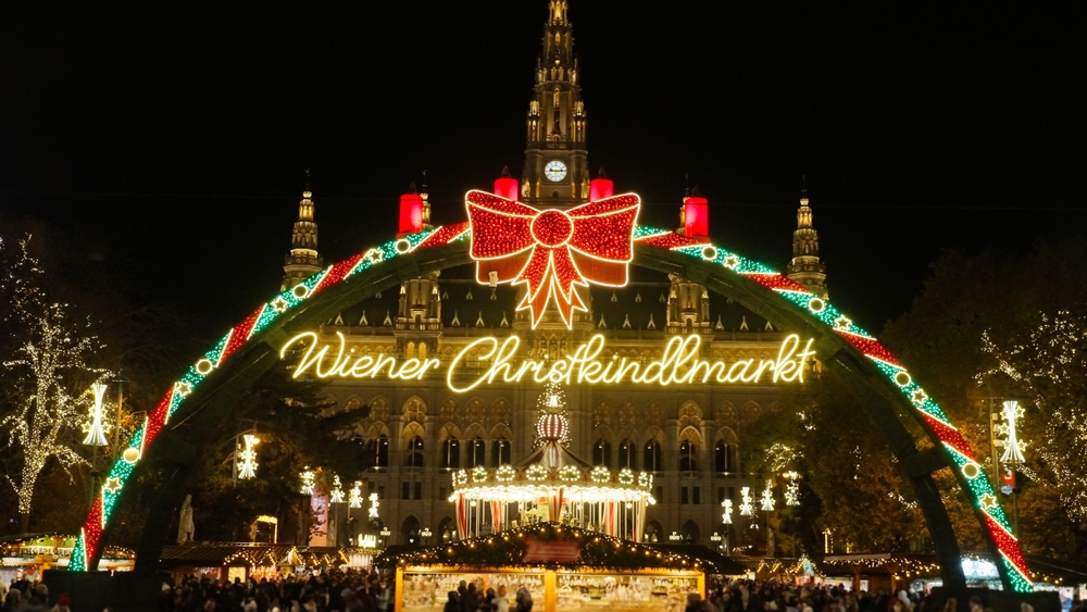 a visit to christmas market with lights and carousel and wooden stalls with crowds