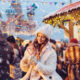 A girl knows what to wear to Christmas markets in Europe as she creates a heart out of candy canes while wearing a knit hat, a chunky coat and more in front of stalls.