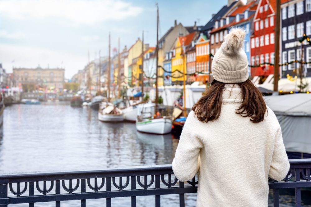 A woman overlooks a canal in Europe, enjoying the view and knowing what to wear in Europe in winter in her fleece jacket and beanie.