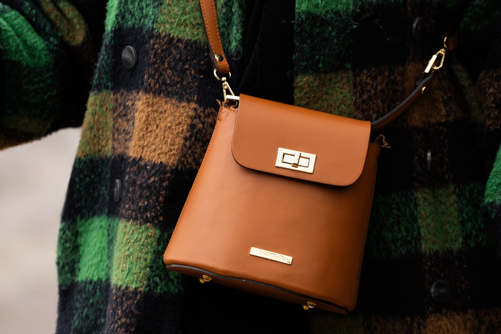 A close up shot shows a style choice when knowing What to Wear in Italy in fall with a plaid jacket and structured crossbody.