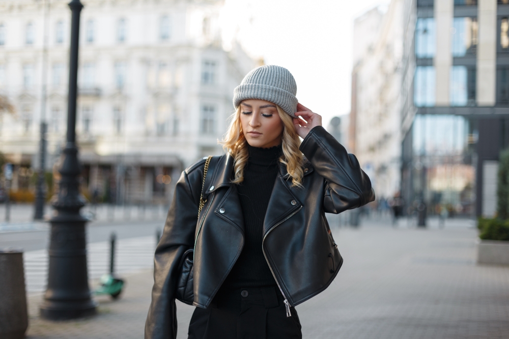 A girl walks down an empty street in a beanie, black turtleneck, leather jacket and beanie: she channels edgy in knowing What to Wear in Italy in fall.