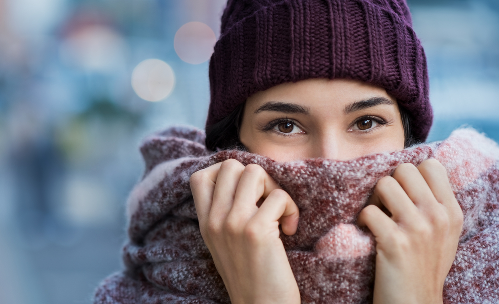 This woman knows what to wear in Italy in winter as she brings her scarf up to cover her nose, and as the scarf's purple and red hues match her purple beanie.