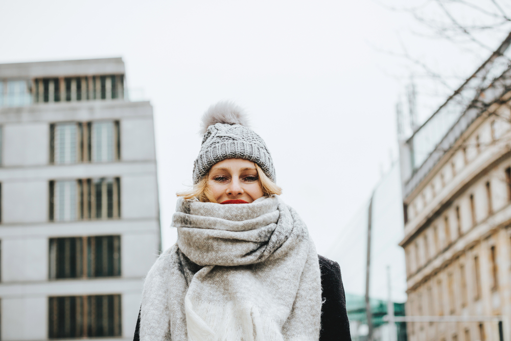 A close up of a woman shows she knows What to Wear in Italy in December in her wrapped scarf that covers her neck and her beanie.