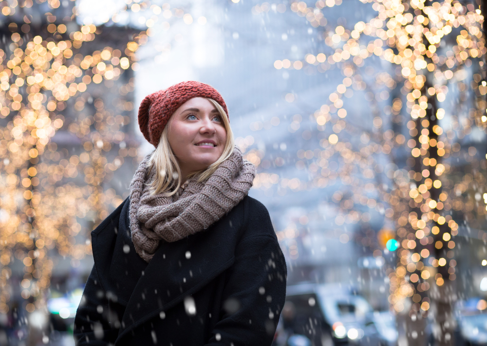A woman knows what to wear in New York City in December with her scarf, wool jacket and beanie keeping her warm as it snows.