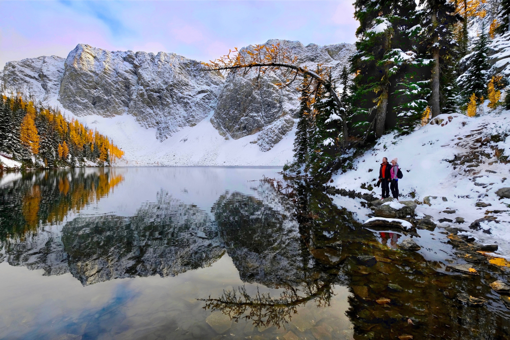A couple standing next to a reflection on a lake in North Cascades Mountains outside of Leavenworth