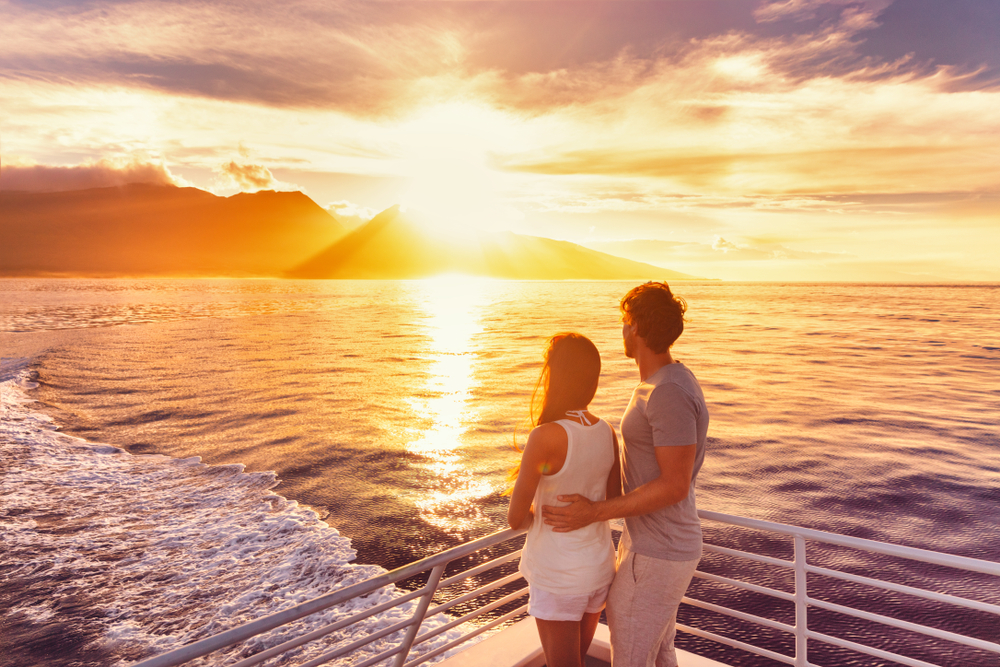 a couple on a boat in hawaii at sunset