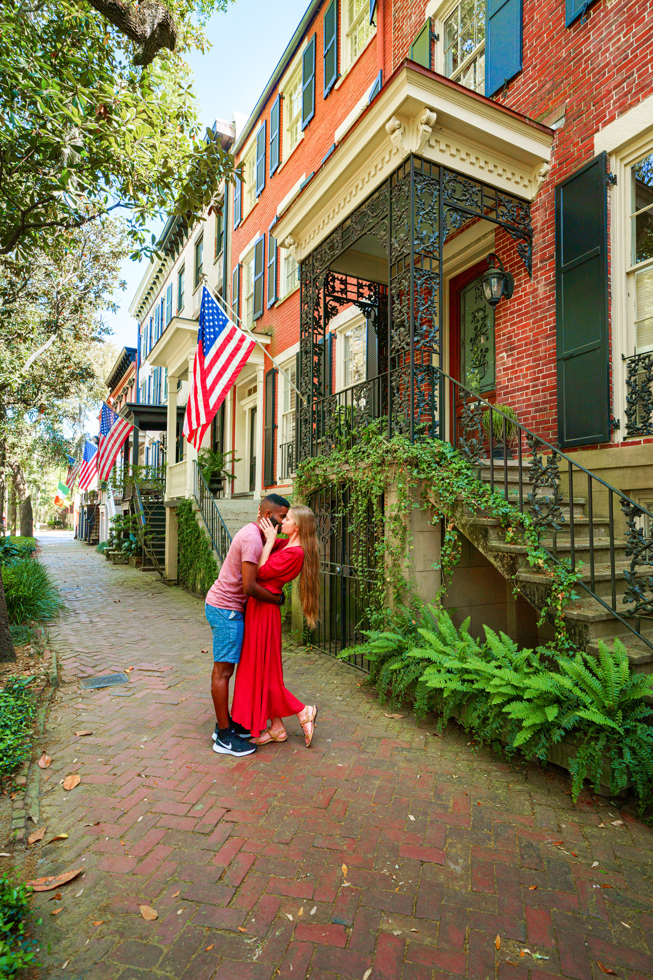 A couple kissing infront of one of the brick historic homes in Savannah Georgia
