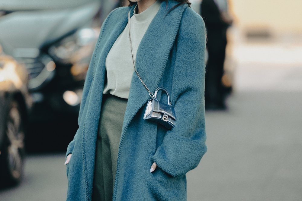 A close up of a woman's outfit shows off her white shirt, chinos and blue trench coat.