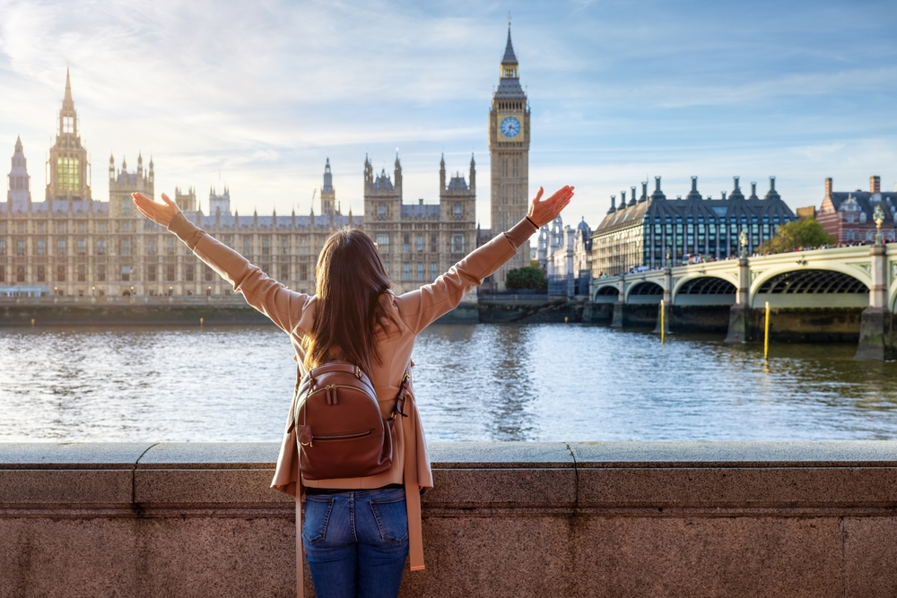 A woman knows what to wear in London in November and prioritizes comfort on this sunny day in her short peacoat, jeans and leather bag.
