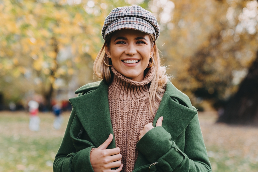 A woman strolls through central park on a cooler day with her hat, knitted turtleneck and wool peacoat.