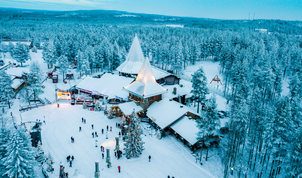 one of the best 21st birthday destinations, finland, snow covered buildings are in the woods with people standing in front of them 