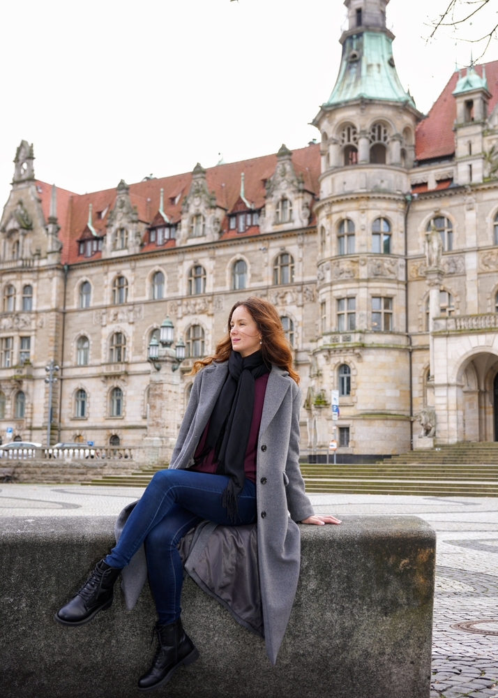 a woman sitting on a wall posing for pictures ina stylish capslue waredrobe