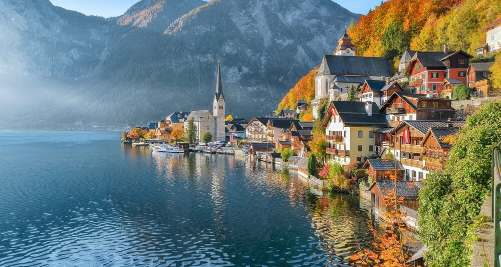 In Northern Europe, which is one place to consider when looking at iconic Europe Trips to Take in 2026, mountains are on the edge of the lake, as are homes, churches, and the trees that fade into fall covers.