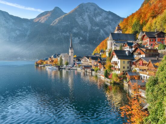 In Northern Europe, which is one place to consider when looking at iconic Europe Trips to Take in 2026, mountains are on the edge of the lake, as are homes, churches, and the trees that fade into fall covers.
