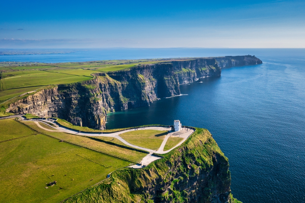 When considering which of the iconic Europe Trips to Take in 2026, look at the chance to take a road trip in Ireland, where the roads spread across the rugged west, by cliffs, as seen in the photo, and green landscape everywhere.