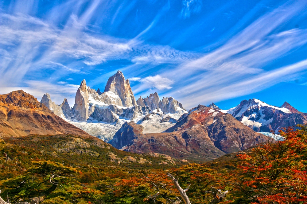 A picturesque landscape photo shows why Argentina is a top pick for iconic World Trips to Take in 2026, with its rugged mountains, blue skies, and sprawling roads and hills with foliage. 
