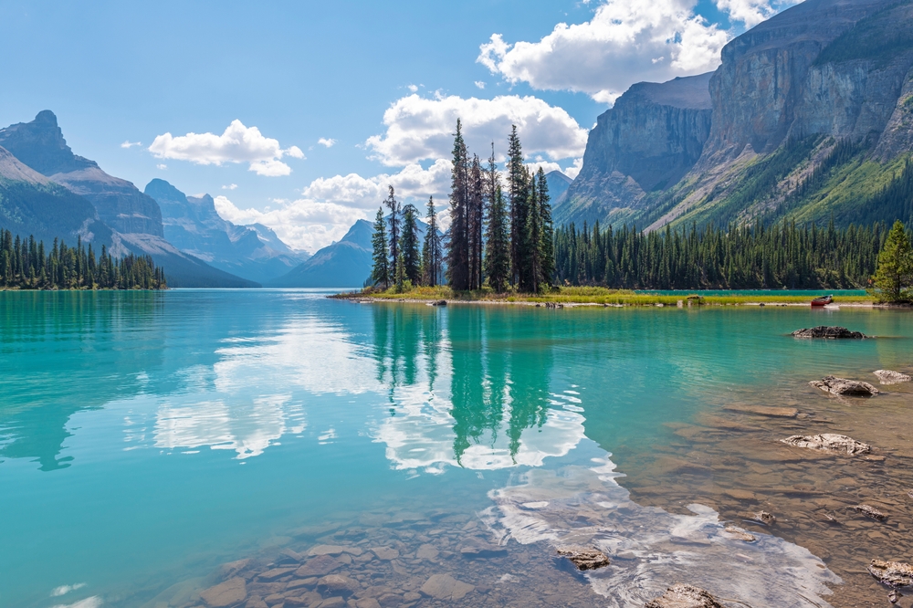 A photo from Canada almost doesn't look real: the blue water looks like glass reflecting trees and mountains and blue skies back, making Jasper one of the iconic World Trips to Take in 2026. 