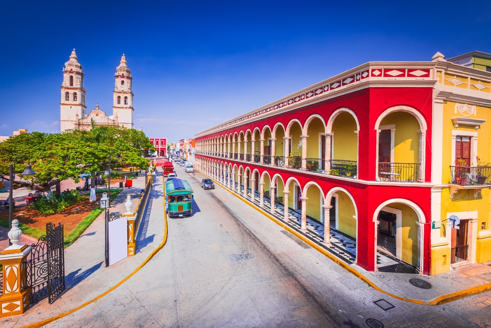 A street view of Mexico shows off the Yucatan Peninsula city style: brightly colored buildings and cars drive by, the culture seeping into the photo, making Mexico one of the iconic World Trips to Take in 2026. 