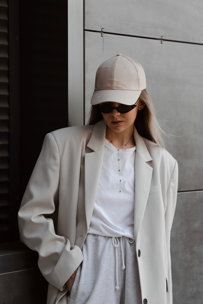 a woman in baseball cap, sweats and blazer on European packing list is chic